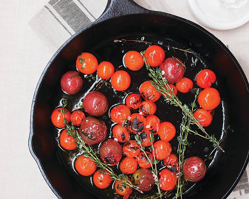 roasted cherry tomatoes and herbs in a cast-iron skillet