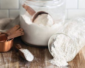 Spilled flour, four scoop, measuring cups, flour container with measuring cup inside