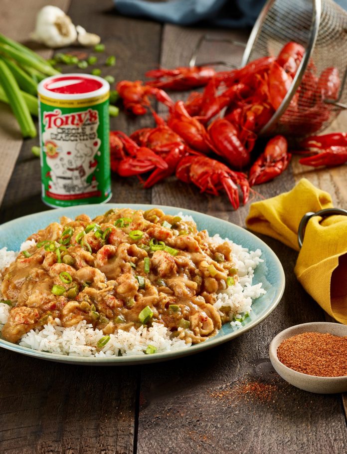 Étouffée on a bed of rice, resting on a table with crawfish and a can of Tony Chachere's seasoning